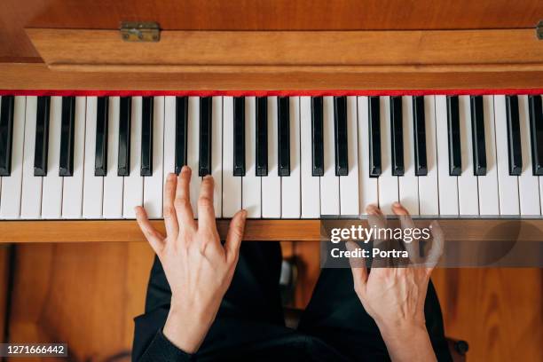 woman practicing upright piano at home - piano imagens e fotografias de stock
