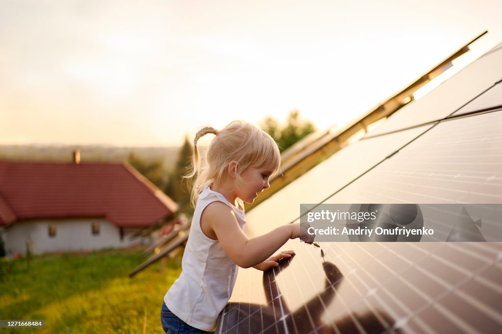 Young girl touching solar panel.