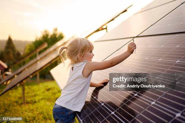 young girl touching solar panel. - solar stock-fotos und bilder