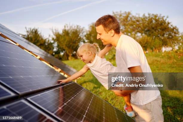 father and daughter touching solar panel - fuel and power generation imagens e fotografias de stock