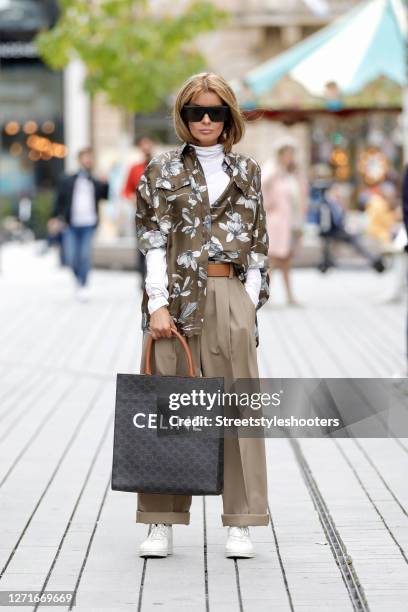 Influencer Gitta Banko wearing a white turtleneck pullover by Brunello Cucinelli, a khaki colored silk blouse with flower print by Brunello...