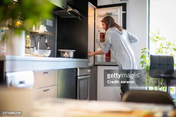 woman opening fridge to find ingredients for lunch - refrigerator stock pictures, royalty-free photos & images