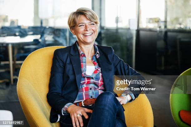 office manager sitting in green chair smiling - gespräch stock-fotos und bilder