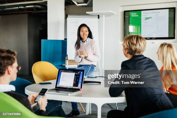 employees listening to colleague's presentation in the office - germany womens team presentation stock-fotos und bilder