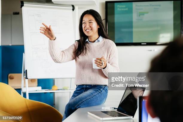 cheerful office employee giving presentation - casual female business leader stock-fotos und bilder