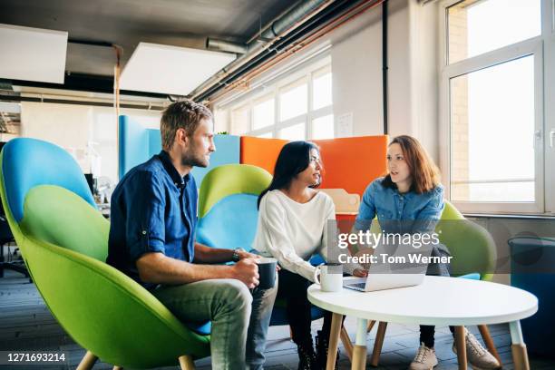 three colleagues talking during meeting in office - ronde tafel stockfoto's en -beelden