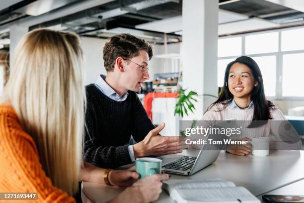 colleagues brainstorming at desk - germany womens team presentation stock pictures, royalty-free photos & images