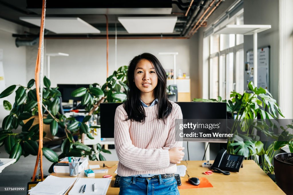 Portrait Of Young Woman Standing At Her Desk