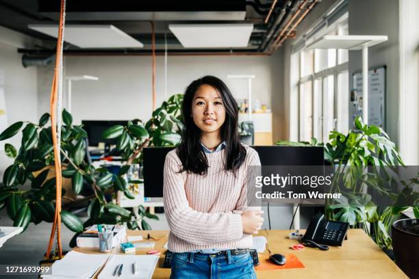 portrait of young woman standing at her desk - asian woman stock-fotos und bilder