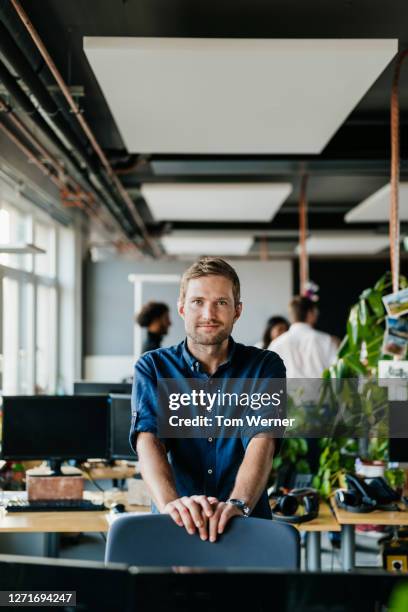 portrait of young office employee leaning on his chair - office portrait uomo foto e immagini stock