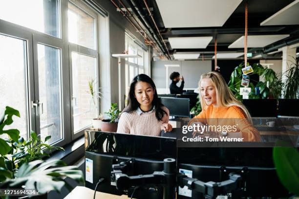 two business associates working at computer together - asian discuss photos et images de collection