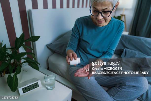 woman taking melatonin pills - slaappil stockfoto's en -beelden