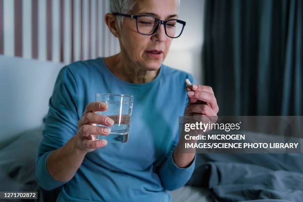 woman taking melatonin pills - slaappil stockfoto's en -beelden