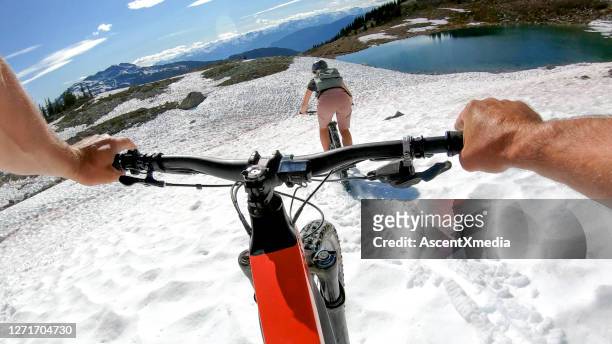 mountain e-bikers ride down snowy mountain slope - whistler stock pictures, royalty-free photos & images