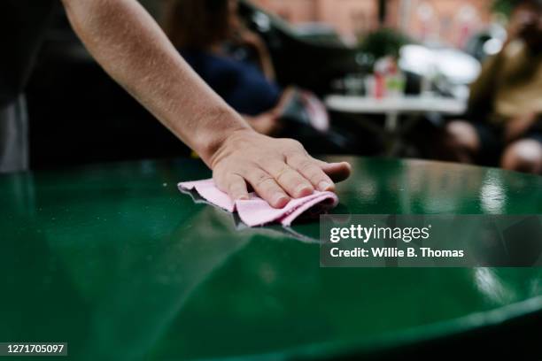 close-up of waitress disinfecting tables at a restaurant - social distancing restaurant stock pictures, royalty-free photos & images