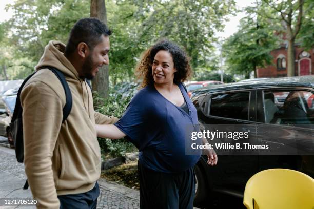 pregnant greeting friend on a city street - pregnant women greeting stockfoto's en -beelden