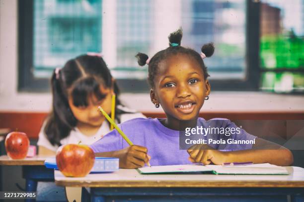 zurück zur schule. bildungskonzept. glückliche afrikanische grundschülerin in der klasse sitzt am ersten schultag am schreibtisch - schwarz ethnischer begriff stock-fotos und bilder
