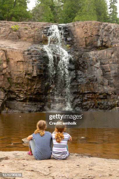 meninas sentadas na rocha olhando para a cachoeira - gooseberry - fotografias e filmes do acervo