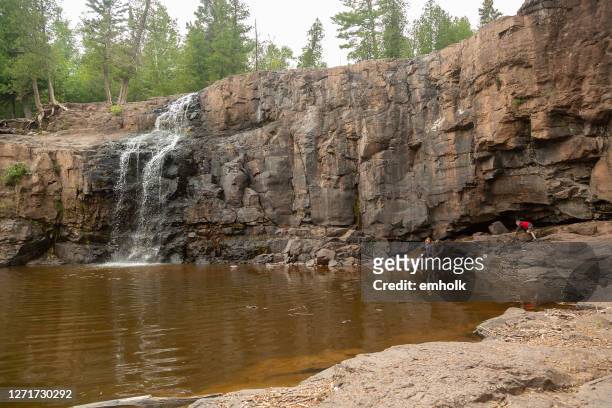 three children exploring cliffs at gooseberry falls waterfall - minnesota river stock pictures, royalty-free photos & images