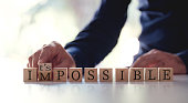 Businessman Changing The Word Impossible To Possible By Flipping Over Wooden Cube.