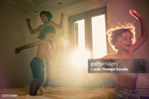 small kids having fun indoor jumping on the bed - bed sun stock pictures, royalty-free photos & images