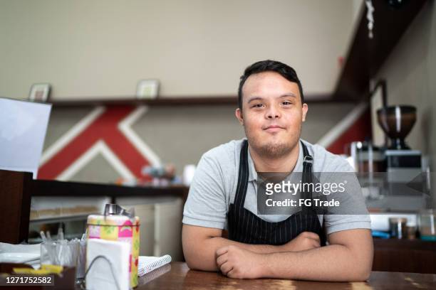 portrait of a special need barista bending over the bar counter - persons with disabilities stock pictures, royalty-free photos & images