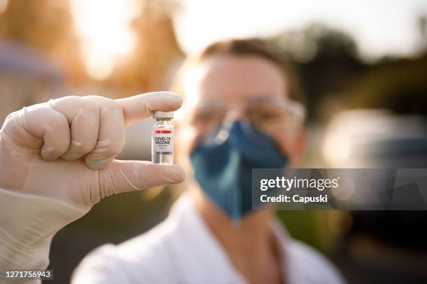 kvinna som innehar covid-19 vaccin injektionsflaska - dose bildbanksfoton och bilder