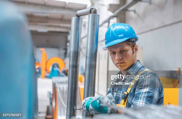 portret van jonge zakenman die met kabelbroodje in fabriek werkt - rolling stockfoto's en -beelden