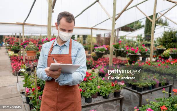 man working at a garden center wearing a facemask during the pandemic - biosecurity stock pictures, royalty-free photos & images