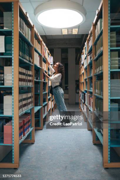 giovane studente che sceglie libri sulla libreria - pick foto e immagini stock