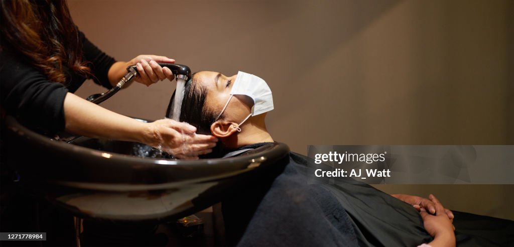 Woman wearing a face mask getting her hair washed in a salon