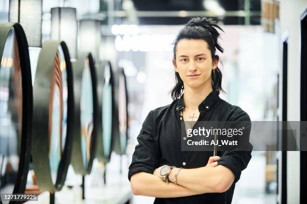 smiling male stylist standing with a comb in a hair salon - topknot stock pictures, royalty-free photos & images
