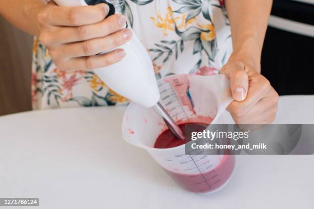 close-up of a woman mixing icing with a hand blender - blender stock-fotos und bilder