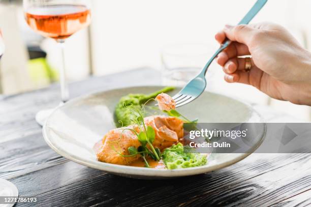 woman eating baked salmon with pea puree - single rose stockfoto's en -beelden