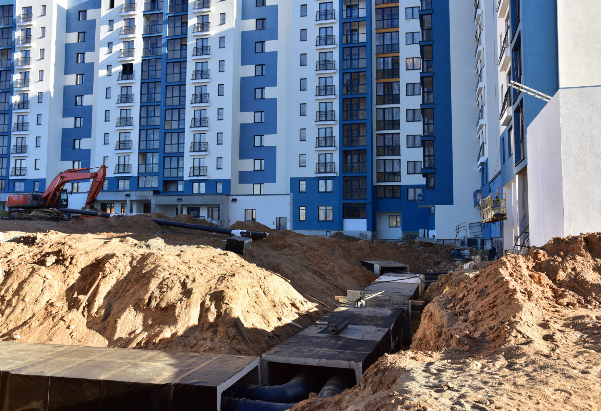 Laying heating pipes in a trench at construction site. Install underground storm systems of water main and sanitary sewer. Cold and hot water, heating and heating system of apartments in the house Laying heating pipes in a trench at construction site. Install underground storm systems of water main and sanitary sewer. Cold and hot water, heating and heating system of apartments in the house