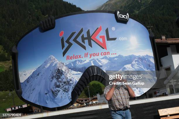 Man removes a protective face mask after photographing himself in front of an advertisement in the shape of ski goggles for the Ischgl ski resort on...