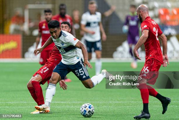 Michael Baldisimo of the Vancouver Whitecaps tries to get past Laurent Ciman and Jonathan Osorio of the Toronto FC during MLS soccer action at BC...
