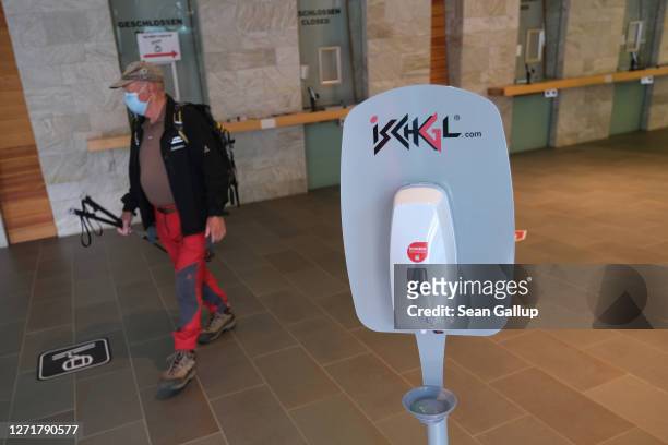 Hiker wearing a protective face mask walks past a disinfectant dispenser at the Silvrettabahn ski lift on September 10, 2020 in Ischgl, Austria....