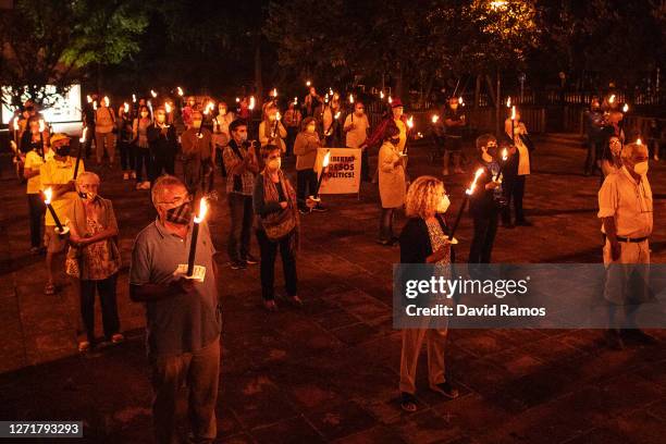 Demonstrators wearing protective face masks observe social distancing guidelines as they gather holding torches during a Catalan Pro-Independence...