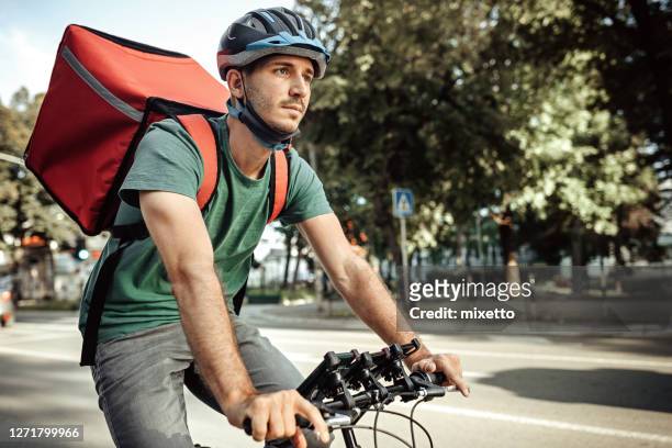 lieferung von lebensmitteln auf dem fahrrad in der stadt - riding hat stock-fotos und bilder