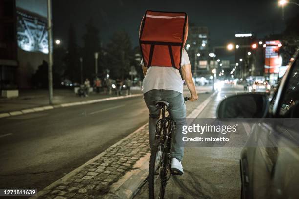 delivering food on bicycle in city at night - night delivery stock pictures, royalty-free photos & images