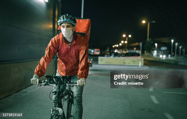 delivering food on bicycle in city at night - night delivery stock pictures, royalty-free photos & images