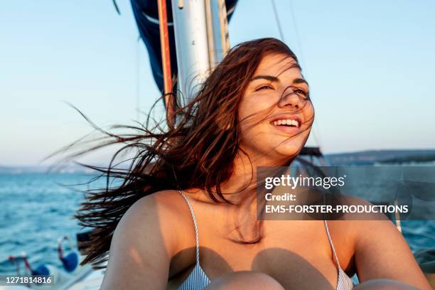 handsome, young women is enjoying the sun on a sail boat - sunset society stock-fotos und bilder