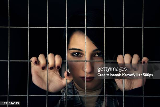 portrait of woman seen through chain link fence, ionnina, greece - woman prison stock pictures, royalty-free photos & images