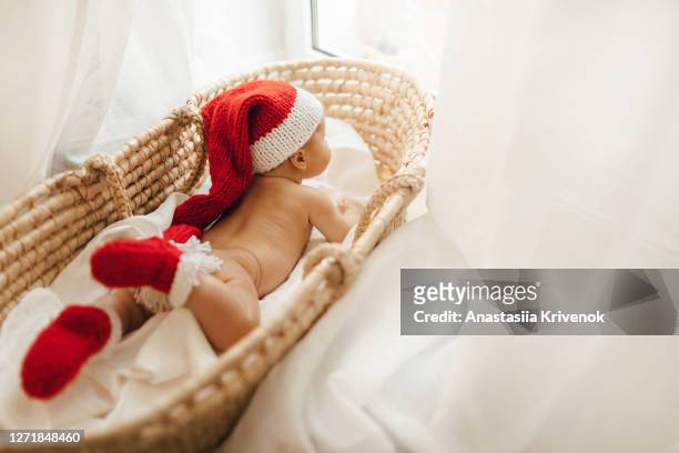adorable naked baby boy wearing a crocheted santa hat and socks lying in moses straw basket at home. little infant girl celebrates christmas. new year's holidays. - hot body girls stock pictures, royalty-free photos & images