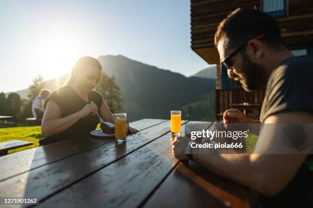 geschichtenerzählen eines tages in den dolomiten: mann und frau gemeinsam in der hütte ausruhen und essen - gardena stock-fotos und bilder