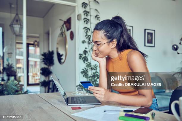 beautiful woman doing finances at home - credit card stock-fotos und bilder