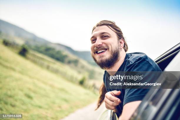 bearded male with long hair enjoying window air cooling while riding in car - macedonia country stock pictures, royalty-free photos & images