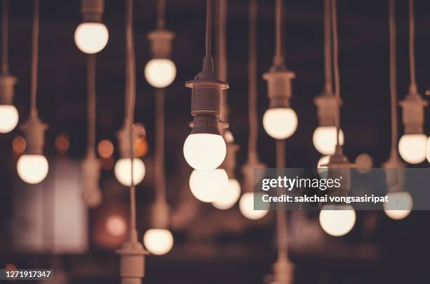 close-up of illuminated pendant lights hanging from ceiling - dark room foto e immagini stock