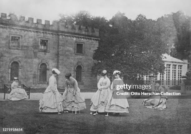 Croquet party, a group of women in Victorian fashions, all wearing bell-shaped skirts, on the lawn at Goodwood House in Westhampnett, Chichester,...